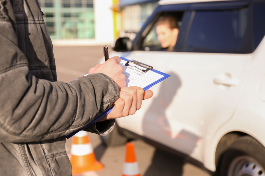 Instructor in driving school writing down results of exam, closeup